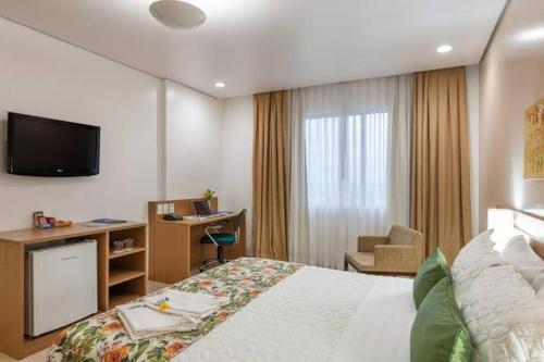 una camera d'albergo con letto, scrivania e TV di Blue Tree a Manaus