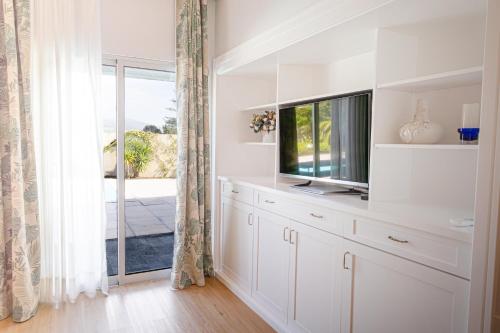 a white living room with a tv and a window at J&B Place in Ponta Delgada