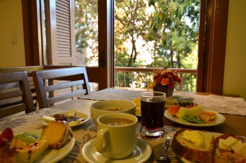 a table with plates of food on a table with a window at Pousada Stillo Gramado in Gramado