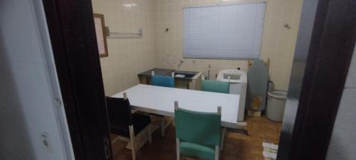a kitchen with a table and some green chairs at Suíte luxo com sacada mobiliada Q2 in Campinas
