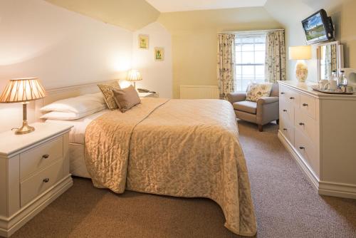 a bedroom with a bed and a chair and a television at Queenshead Hotel Kelso in Kelso