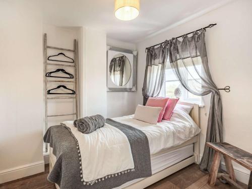 a bedroom with a bed with pink pillows and a window at 2 Bed in Holt 87768 in Baconsthorpe