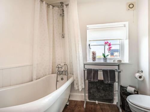 a bathroom with a tub and a sink and a window at 2 Bed in Holt 87768 in Baconsthorpe