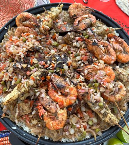 a black plate of food with shrimp and rice at ChezBabo Wellness Hotel in Ngaparou