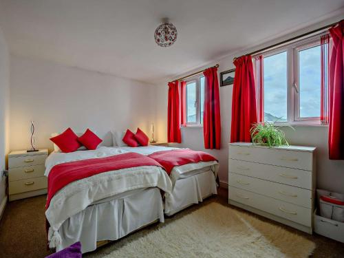a bedroom with red curtains and a bed with red pillows at 1 Bed in Troutbeck nr Ullswater SZ254 in Troutbeck