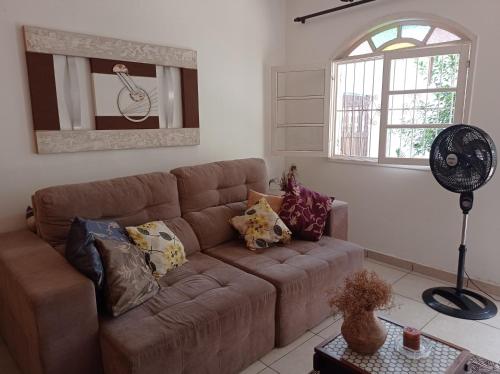 - un salon avec un canapé brun et une fenêtre dans l'établissement Casa Aconchegante., à Cabo Frio
