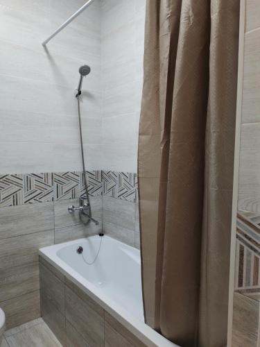 a bath tub with a shower curtain in a bathroom at ЖК Брюссель in Taldykolʼ