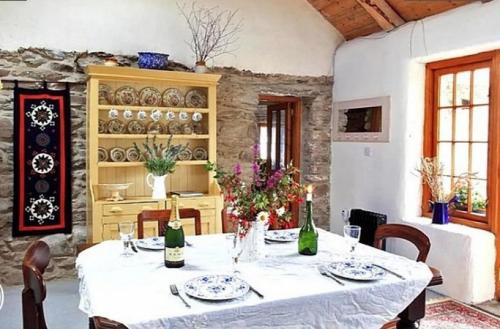 un comedor con una mesa blanca con sillas y botellas de vino en Phils Cottage en Kenmare
