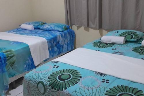 Zimmer mit 2 Betten mit blauer und grüner Bettwäsche in der Unterkunft Casa DOM Santo Amaro do Maranhão in Santo Amaro