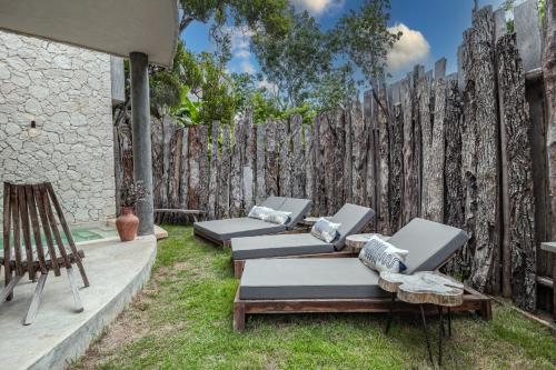 a row of chaise lounges in a backyard with a fence at 3BD Luxury Villa Private pool & with special fee to access Hotel Bardo 4B in Tulum