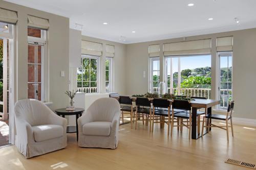 a dining room with a table and chairs and windows at Grande Vista 5Br Manor with Pool & Mt Eden Views in Auckland