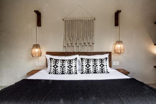 een slaapkamer met een bed met zwart-witte kussens bij 3BD Luxury Villa Private pool & with special fee to access Hotel Bardo 4B in Tulum