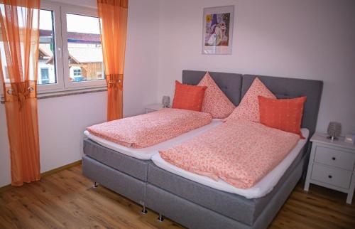 - une chambre avec un lit et des oreillers orange dans l'établissement Ferienwohnung 2 Schlafzimmer Nähe Legoland Günzburg mit Balkon und herrlichem Fernblick, à Burtenbach