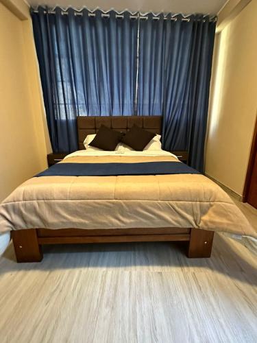 1 dormitorio con 1 cama grande y cortinas azules en Gran Hotel, en Yungay