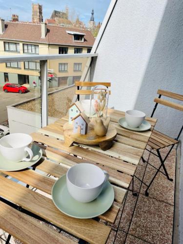 une table en bois avec des tasses et des assiettes sur un balcon dans l'établissement Duplex au cœur de Béthune 3 étoiles, à Béthune