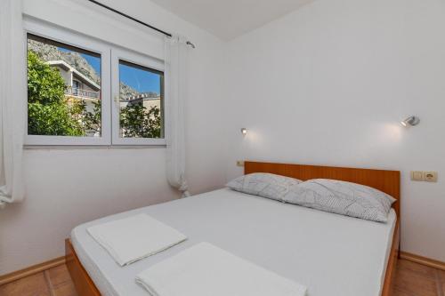 a bedroom with a white bed and two windows at Apartments with a parking space Podaca, Makarska - 6050 in Podaca