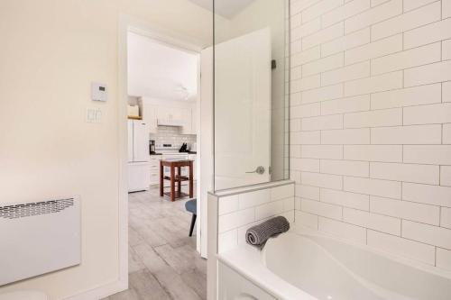 een witte badkamer met een bad en een keuken bij Un Havre de Bonheur in Saint Adolphe D'Howard