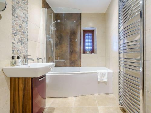 Un baño con bañera blanca y lavabo. en 4 Bed in Bamburgh 83373, en Belford
