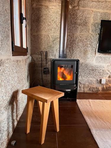 a wooden table next to a fireplace with a stove at Casa María da Reza in Ribadavia