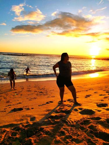 two people standing on the beach at sunset at Hotel Los Algarrobos in Puerto Baquerizo Moreno