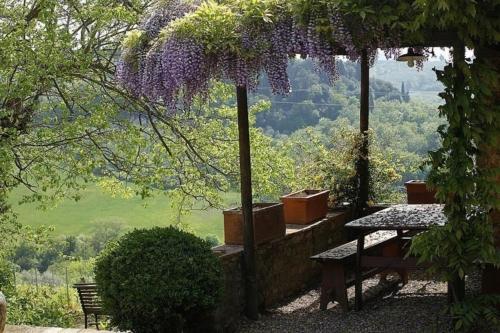 un patio con una mesa y flores colgando de un árbol en Casa Corzanello, en San Casciano in Val di Pesa