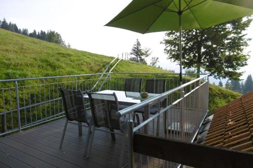 una mesa y sillas en una terraza con sombrilla en Ferienwohnung auf dem Bauernhof- ideal für Familien mit Kindern, en Sulzberg