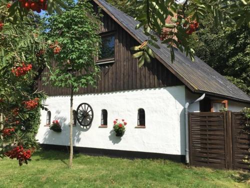 a white barn with two windows and a wheel at Ferienhaus Knorburg im Herzen Nordfrieslands in Enge-Sande