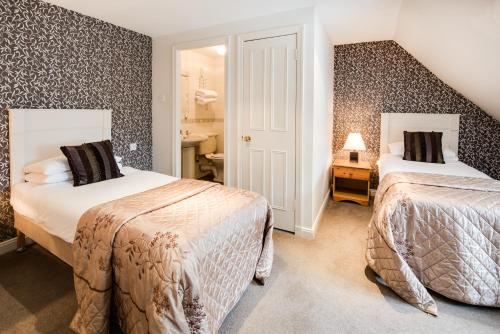 a hotel room with two beds and a bathroom at Queenshead Hotel Kelso in Kelso