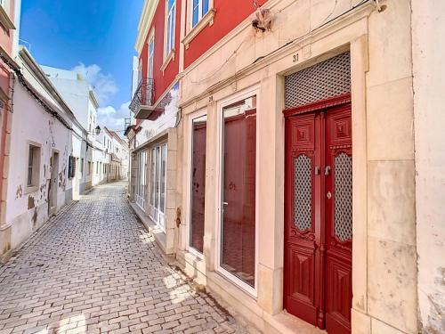an alley with red doors on a building at CASA NOAVA in Loulé