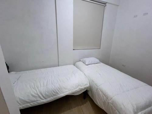 twee bedden in een kleine kamer met witte muren bij Mini apartamento en Ayacucho in Ayacucho