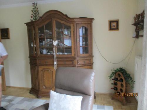 a wooden cabinet in a living room with a chair at Wohnung in Pidingerau mit Großer Terrasse in Piding