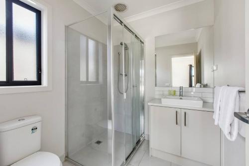 ein weißes Bad mit einer Dusche und einem Waschbecken in der Unterkunft Melton Moments - Cheerful and Breezy Living in Melton