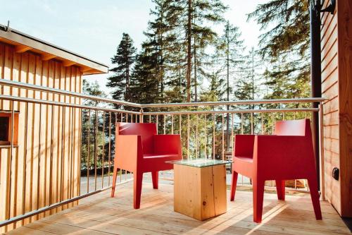 dwa krzesła i stół na balkonie z drzewami w obiekcie Ferienhaus in Zona Artigianale San Felice mit Grill und Terrasse w mieście Tret
