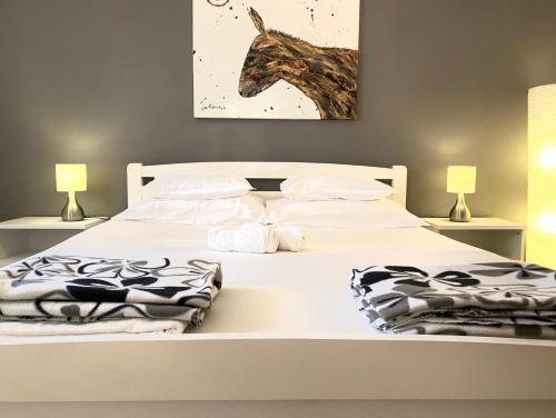 een slaapkamer met een wit bed en een schilderij van een paard aan de muur bij Strandnahes, kleines Ferienhaus mit schattiger Terrasse und Gartennutzung, ruhig gelegen in der Nähe von Zadar in Bibinje
