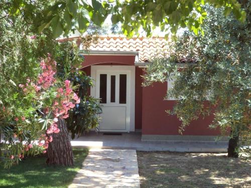 een rode garage met een witte deur en enkele bomen bij Strandnahes, kleines Ferienhaus mit schattiger Terrasse und Gartennutzung, ruhig gelegen in der Nähe von Zadar in Bibinje
