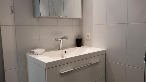 a white bathroom with a sink and a mirror at KLAPROOS Bed by the Sea in Westkapelle