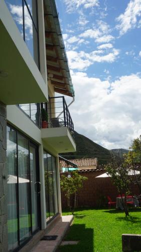 a house with a balcony and a grass yard at Andahuaylillas Quedate Aqui in Andalmailillas