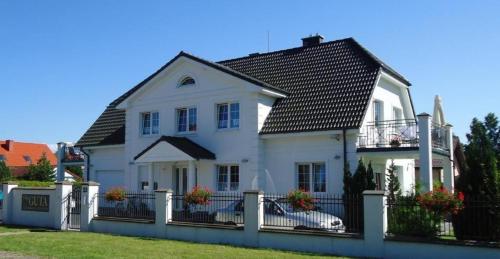 una casa bianca con una recinzione e una macchina di Wohnung in Rowy mit Grill, Terrasse, Parkplatz und Garten a Rowy