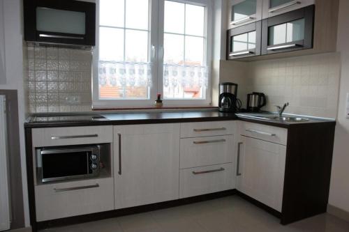 una cucina con armadi bianchi, lavandino e forno a microonde di Wohnung in Rowy mit Grill, Terrasse, Parkplatz und Garten a Rowy