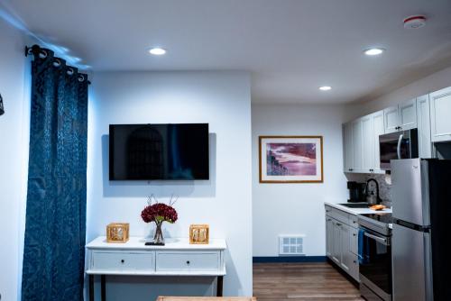 a kitchen with white cabinets and a tv on the wall at Palmer Suite 101, Hyland Hotel in Palmer