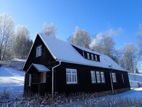 a black house with snow on the roof at Ferienhaushälfte Gösselberg im Ferienhaus Anno Dazumal, wie zu Großmutters Zeiten, linke Seite in Klingenthal