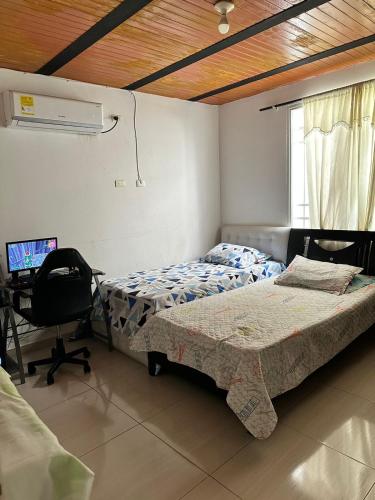 um quarto com 2 camas e uma secretária com um computador em Habitación temporada festival em Valledupar