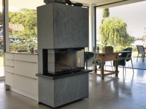 a kitchen with a fireplace and a table in a room at Haus am See Storkow in Storkow