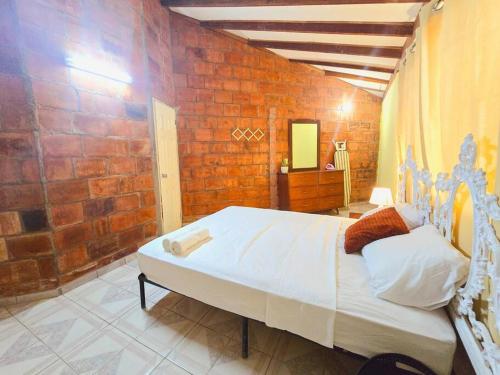 a bedroom with a large bed and a brick wall at Años Dorados - Casa rústica a 200 mts de la Playa Punta Chame in Punta Chame