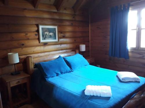ein Schlafzimmer mit einem blauen Bett in einem Blockhaus in der Unterkunft cabaña junto al arroyo in San Martín de los Andes