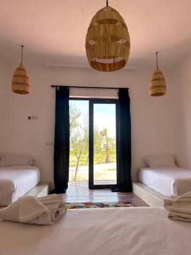 um quarto com duas camas e uma janela em Aghmat Lodge Guest house em Marrakech