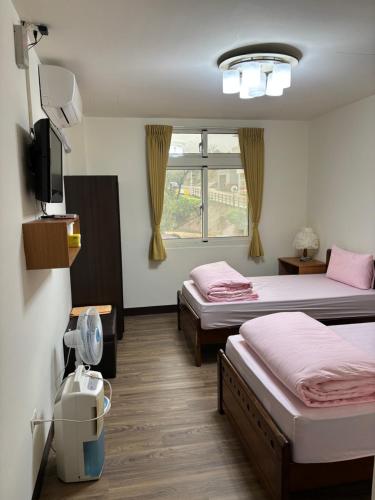 ein Hotelzimmer mit 2 Betten und einem TV in der Unterkunft 今友緣二館民宿 in Dongyin/