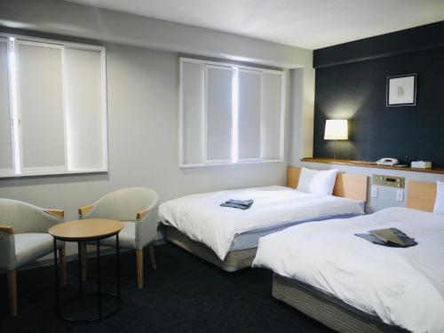 伊萬里市的住宿－伊万里中央酒店，酒店客房带两张床和一张桌子以及椅子。