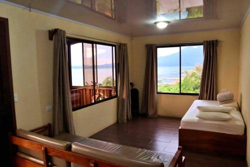 1 dormitorio con 2 camas y 2 ventanas grandes en Love House Arenal-Volcano & Lake views, en Fortuna