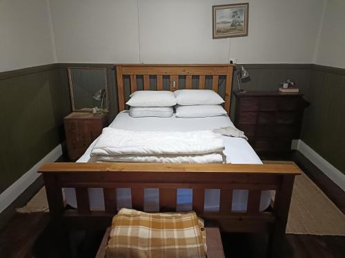 1 dormitorio con 1 cama con sábanas y almohadas blancas en Timbermiller's cottage, en Deeside